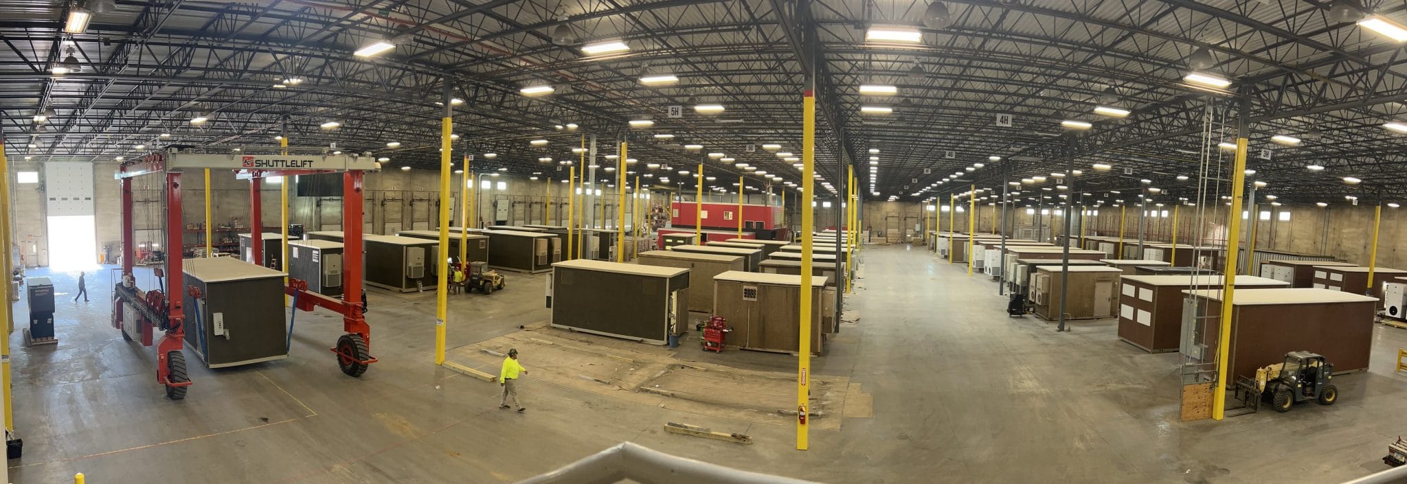 A panoramic view of the warehouse facility at CellSite Solutions where you can see concrete shelters arranged in aisles by the Shuttlelift crane.