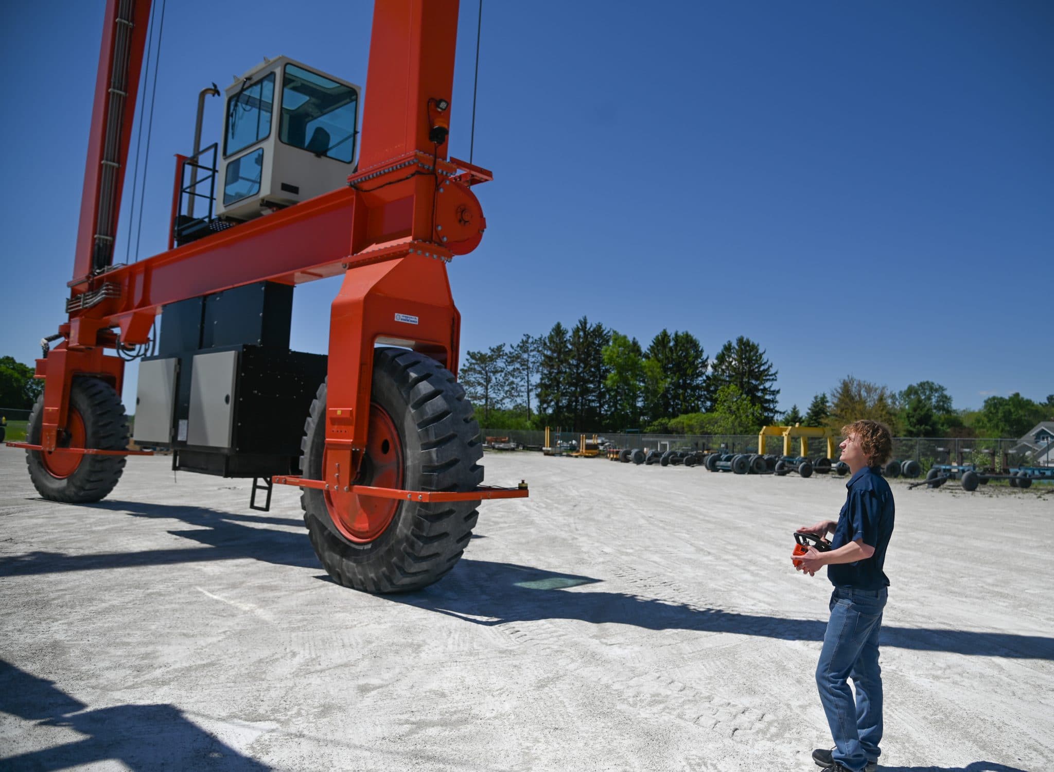 Young man operates a large mobile gantry crane with a wireless remote.